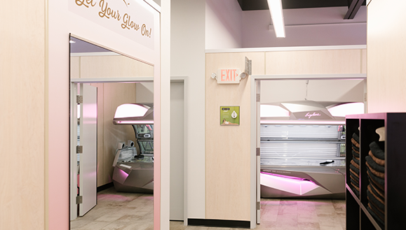 Inside of a Sun Tan City Salon. Sunbed booth and a mirro on the left hand side and a cubby for towels on right side
